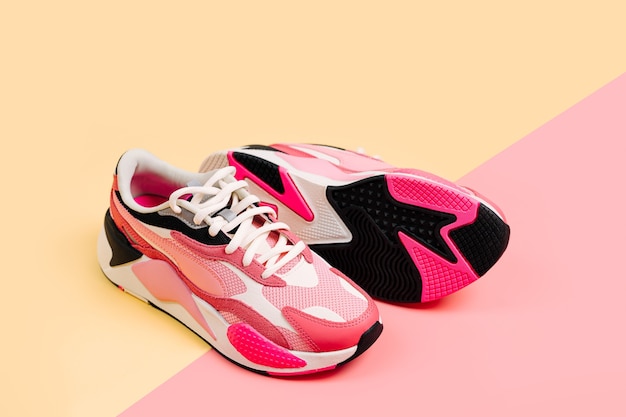 Heldere vrouwelijke sneakers op roze achtergrond. Mode blog of tijdschrift concept. Damesschoenen, trendy sneakers, mode, stijl, lifestyle.