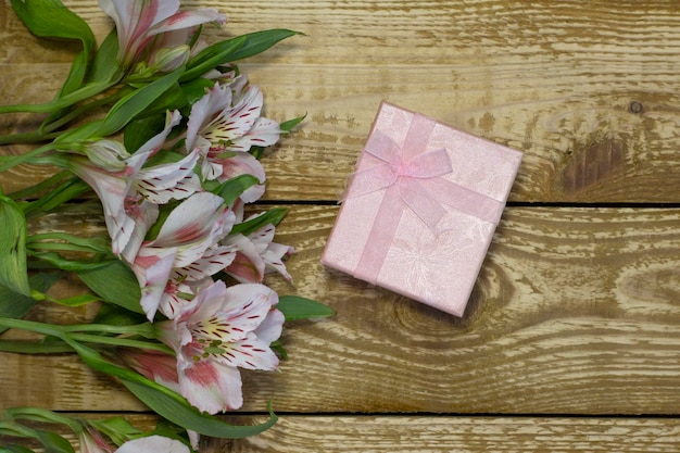 Heldere witte en roze bloemen Alstroemeria en roze papier verpakt geschenkdoos op houten gestructureerde achtergrond close-up