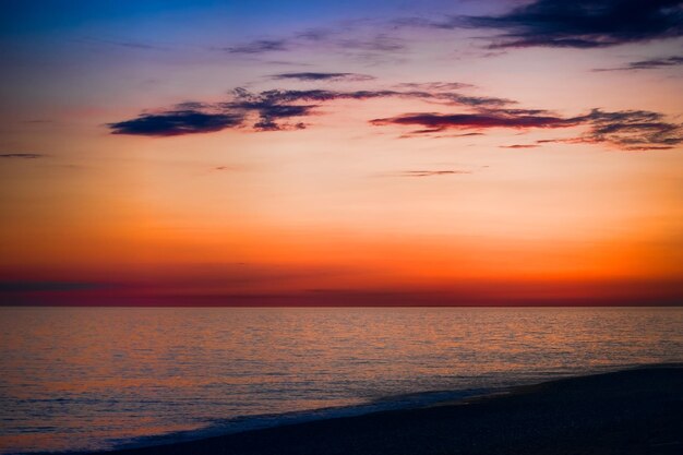 heldere zonsondergang over de blauwe zee met glinsterende verschillende kleuren in de wolken