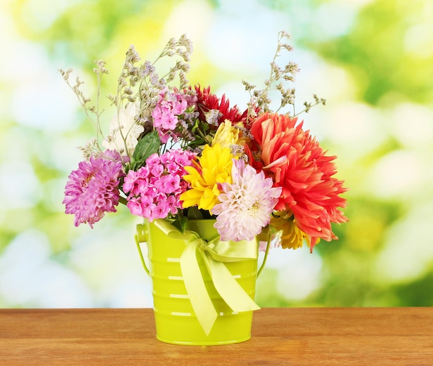 Heldergroene emmer met bloemen op groene achtergrond