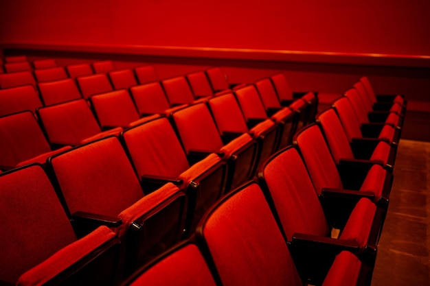 Helderrode zaal met rijen lege, met rode doek bedekte zitplaatsen
