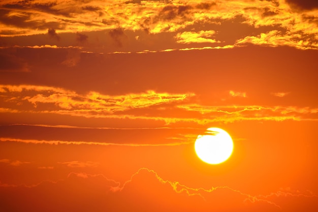 Helderwitte ondergaande zon tegen een oranje lucht bij avondzonsondergang