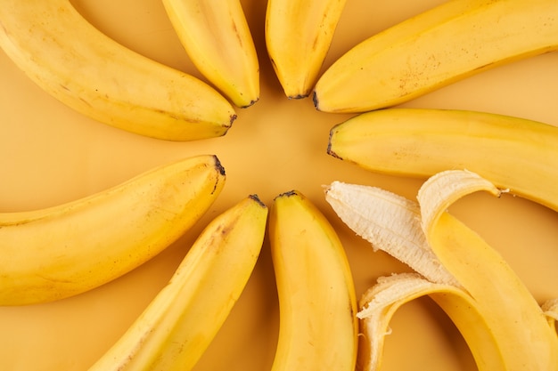 Hele bananen met schilpatroon op gele achtergrond, fruitbehang