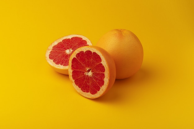 Hele en gesneden grapefruit op gele achtergrond