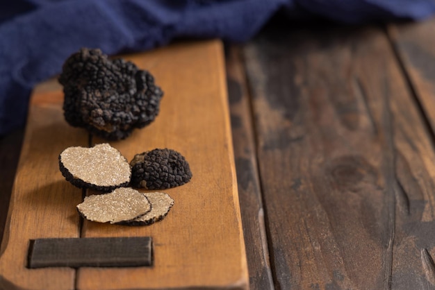 Hele en gesneden zwarte truffels paddenstoel op houten bord op donkerbruine tafel close-up