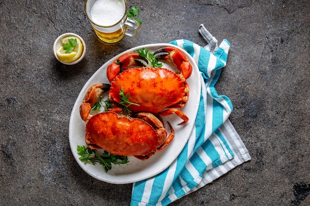 Hele gekookte krabben op een wit bord met citroen en bier grijs betonnen achtergrond bovenaan
