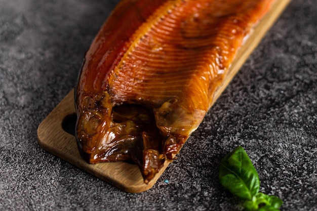 Hele gerookte forel op een houten bord op een donkere achtergrond Snack