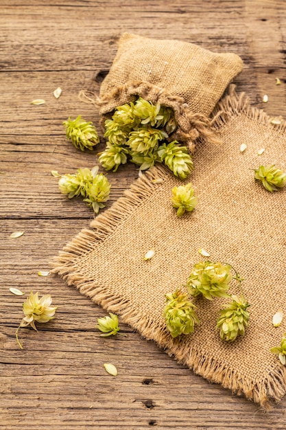 Hele hop in zak op houten oude tafel. Brouwerij. Bier ingrediënten. Zak met hop op vintage planken