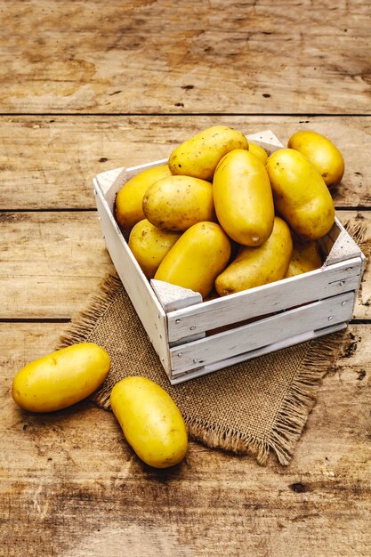 Hele ongeschilde rauwe aardappelen in een houten kist. Nieuwe oogst, op zak, houten planken achtergrond