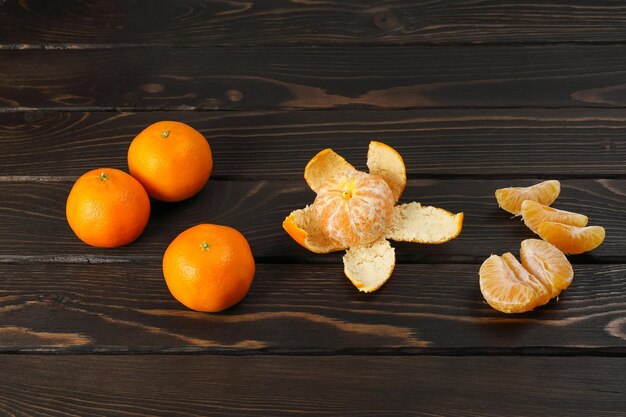 Hele oranje mandarijnen en gezien vanaf de schil met aparte sappige plakjes op houten oppervlak