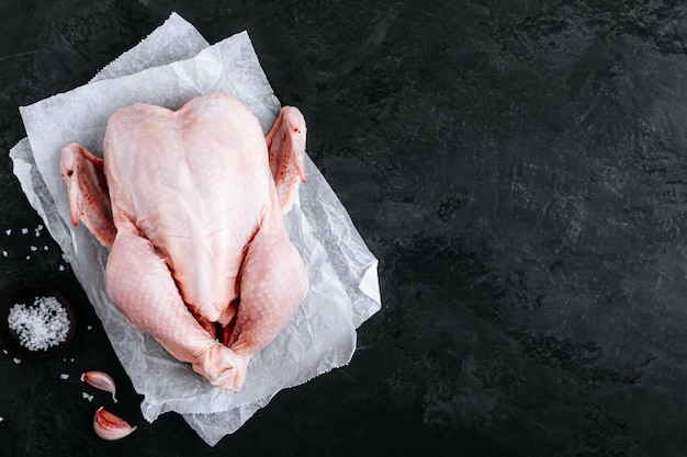 Hele rauwe kip klaar om te koken Biologische kip met vrije uitloop op donkere stenen achtergrond Bovenaanzicht kopieerruimte