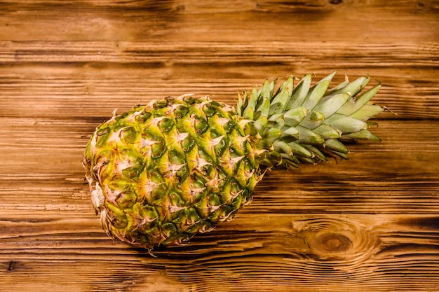 Hele rijpe ananas op rustieke houten tafel. Bovenaanzicht