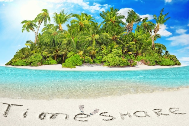 Hele tropisch eiland binnen atol in tropische Oceaan. Onbewoond en wild subtropisch eiland met palmbomen. Inscriptie "TimeShare" in het zand op een tropisch eiland, Malediven.