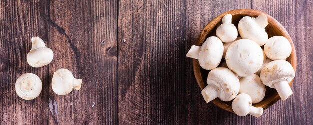 Hele verse champignons in een bord en op een houten tafelblad webbanner