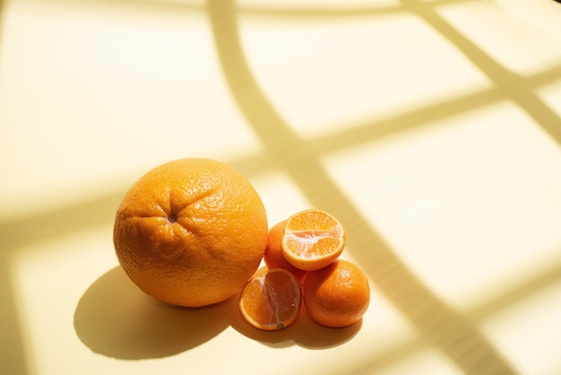 Helften van verse, sappige mandarijn, sinaasappel, in zonlicht met geometrische schaduwen, close-up. Citrus vruchten.