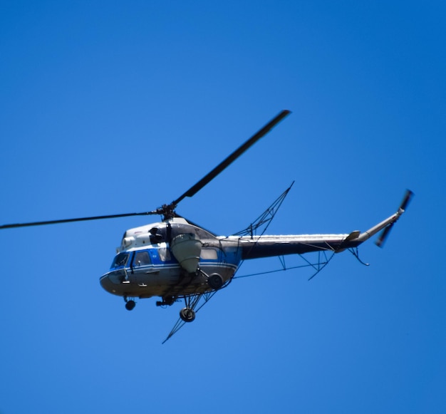 A helicopter of agricultural aviation is flying in the blue sky