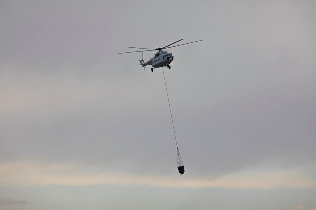 helicopter extinguishes a fire from a basket of water