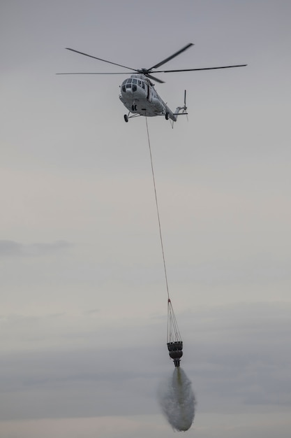 helicopter extinguishes a fire from a basket of water