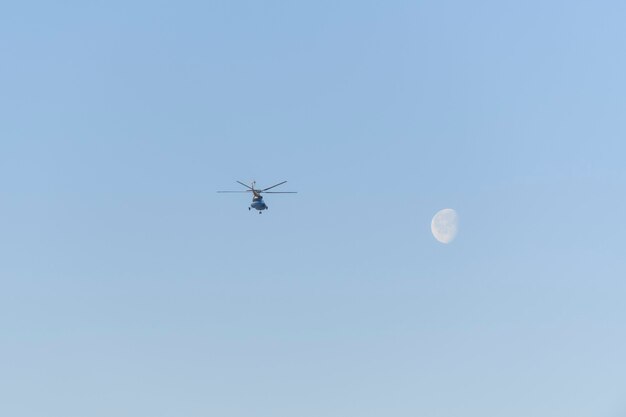 Elicottero che vola nel cielo blu con la luna.