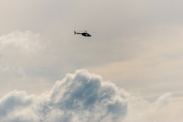 Helicopter flying on dramatic sky background.