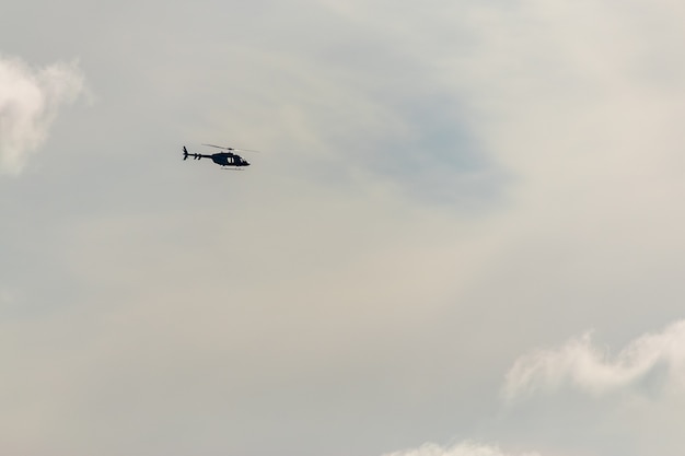 Helicopter flying on dramatic sky background.