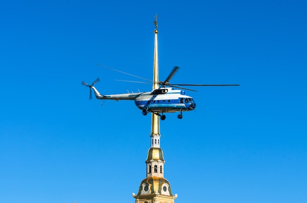 Helikopter in de lucht tegen de torenspits van de Peter en Paul-vesting in Sint-Petersburg.