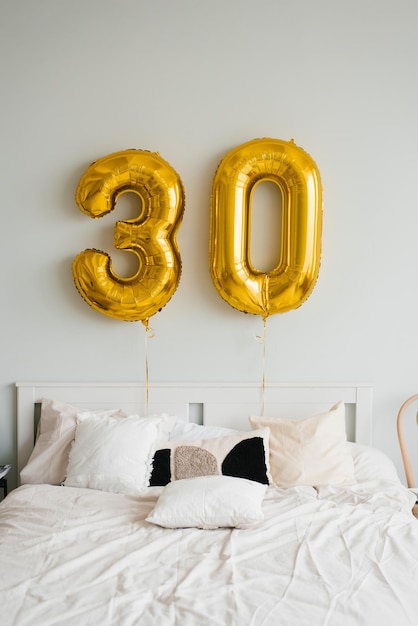 Heliumballonnen voor 30 jaar boven het jarige of jarige bed in huis Feestelijke ochtend