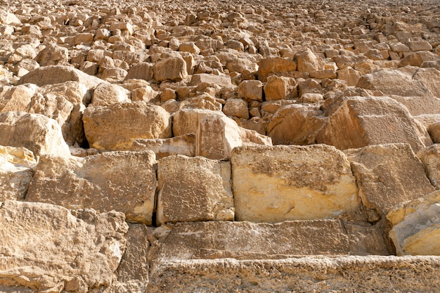 Foto helling van drie grote piramide van gizeh-piramidecomplex en lucht erachter. achtergrond van piramidebakstenen. stenen muur van egyptische piramides in giza, close-up