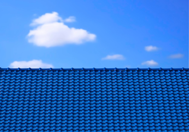 Hellinghoekweergave van glanzend blauw dak van keramische tegels met vage witte wolk op blauwe hemelachtergrond