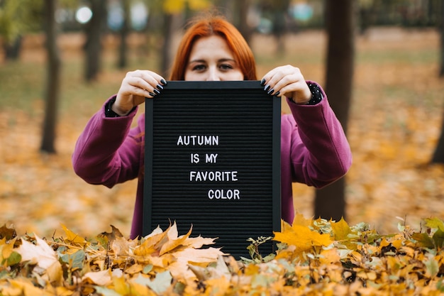 Foto ciao ragazza dai capelli rossi autunnali con bacheca di lettere con testo l'autunno è il mio colore preferito