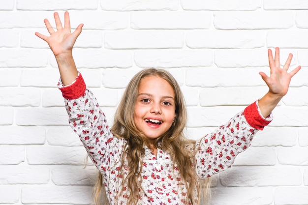 Photo hello everyone happy girl smiling face happy childhood emotional expression so good to be at home small kid happy baby carefree smiling child with long hair simple happiness concept