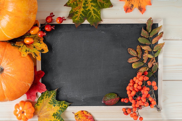 Hello fall pumpkins berries and fallen leaves with chalk blackboard