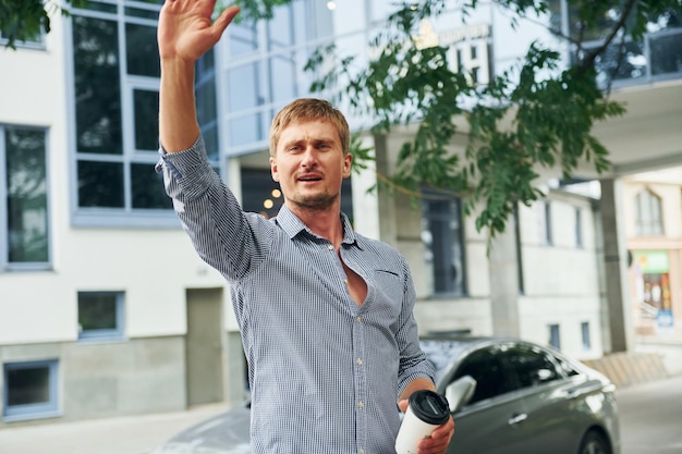 Hello gesture Raises his hand up Man having a walk outdoors in the city at daytime