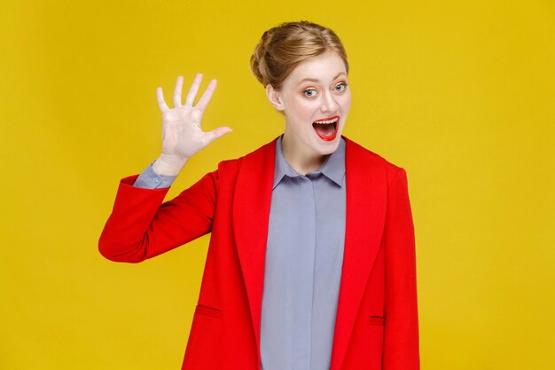 Hello ginger red head business woman in red suit showing hi sign