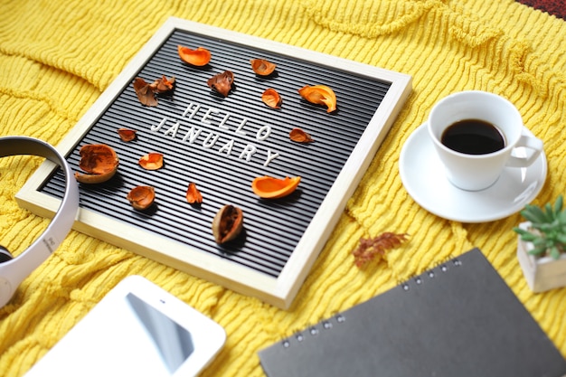 Hello January written on the letter board with multimedia accessories and coffee flat lay concept