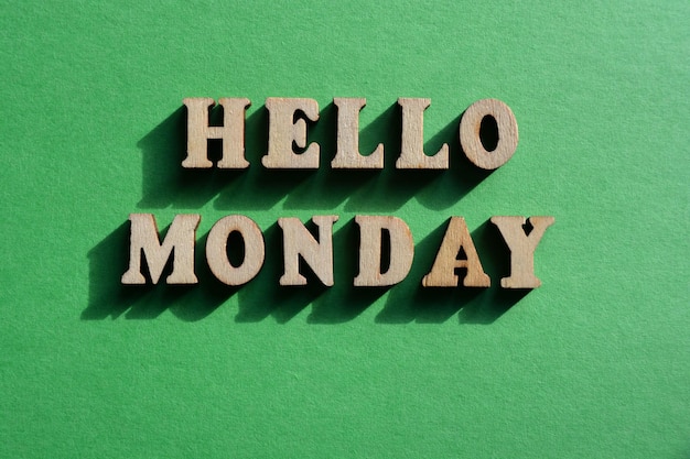 Hello Monday words in wooden alphabet letters isolated on green background