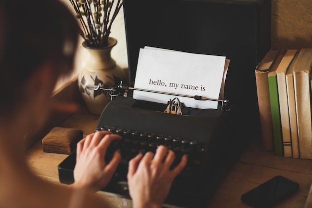 Photo hello, my name is against young woman using typewriter