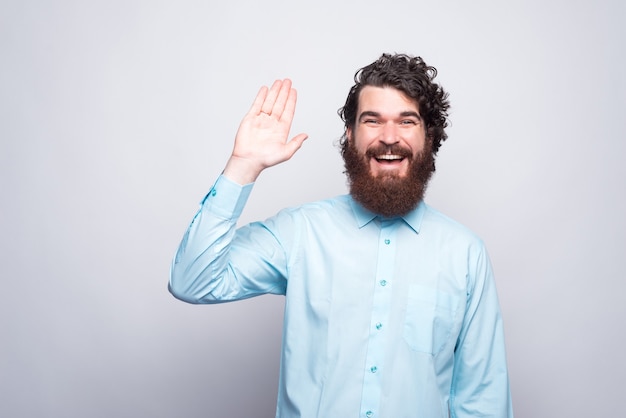 Hello people, smiling bearded man in casual saluting gesture.