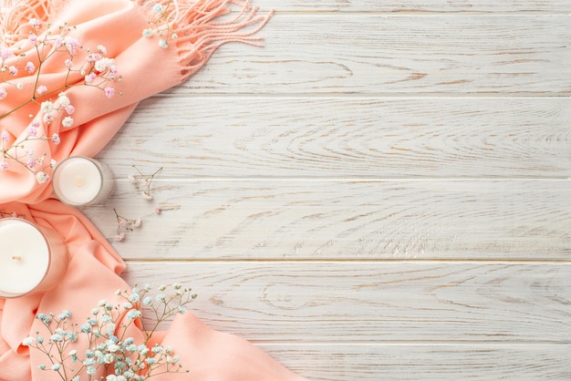 Hello spring concept Top view photo of candles gypsophila flowers and pink scarf on grey wooden desk background with copyspace