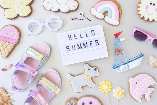 Hello summer text on lightbox and cute summer symbols on grey background Top view Flat lay Creative summer concept greeting card