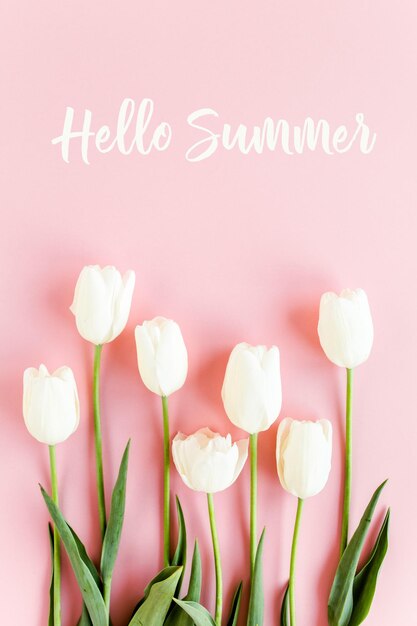 Hello summer text white tulips on pink background minimal floral concept greeting card flat lay top