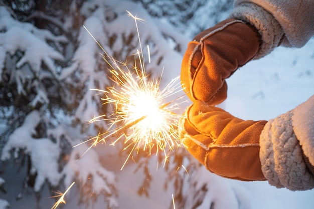 Hello winter cozy winter mood a girl in a white fur coat and warm mittens holds sparklers in her han...
