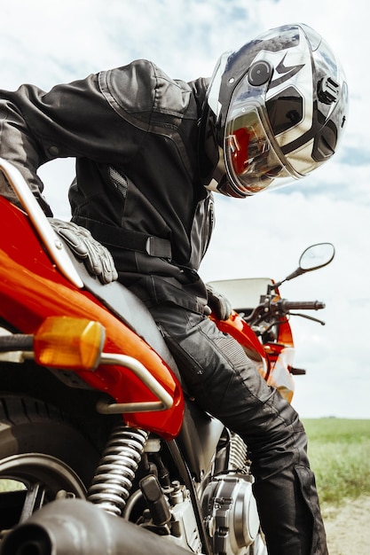 Motociclista con casco seduto sulla motocicletta guardando il primo piano della ruota posteriore