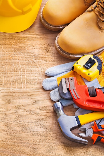 Helmlaarzen handschoen tapeline aapsleutel hamertangen op houten plank