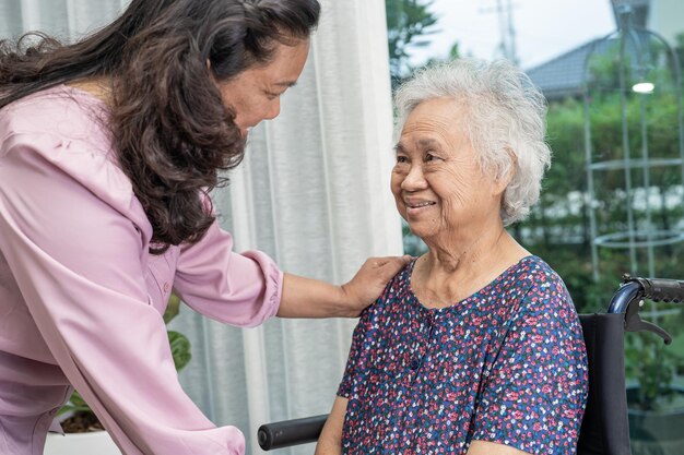 Help and care Asian senior or elderly old lady woman patient sitting on wheelchair at nursing hospital ward healthy strong medical concept