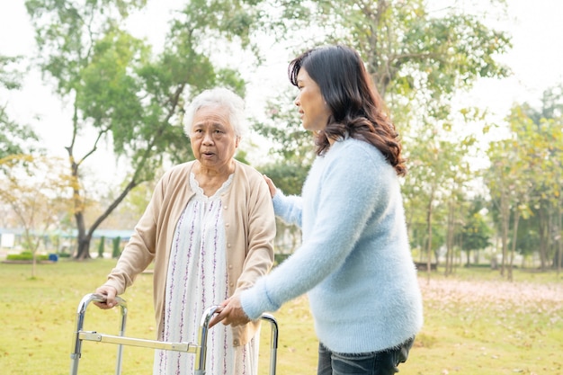 Aiuta e cura il camminatore senior asiatico di uso della donna in parco.