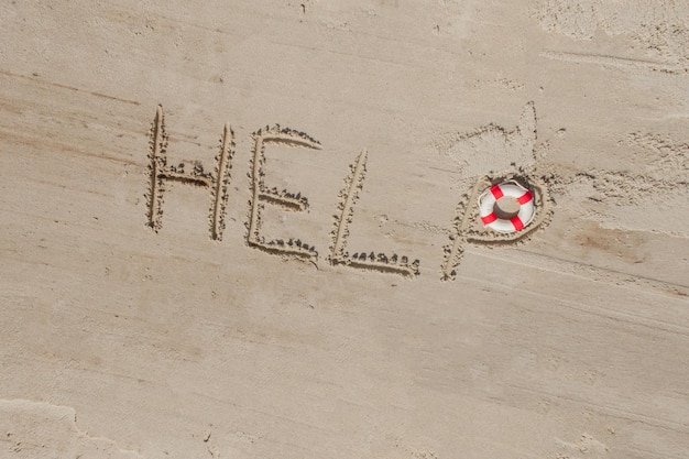 Help me de inscriptie en reddingsboei op het zand Help me alsjeblieft op een tropisch strand