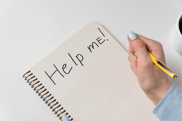 Foto aiutami a scrivere sul taccuino su sfondo bianco. mano femminile che scrive nel quaderno