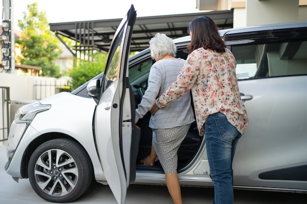 Aiutare e sostenere la paziente anziana o anziana asiatica anziana prepararsi per raggiungere la sua auto.