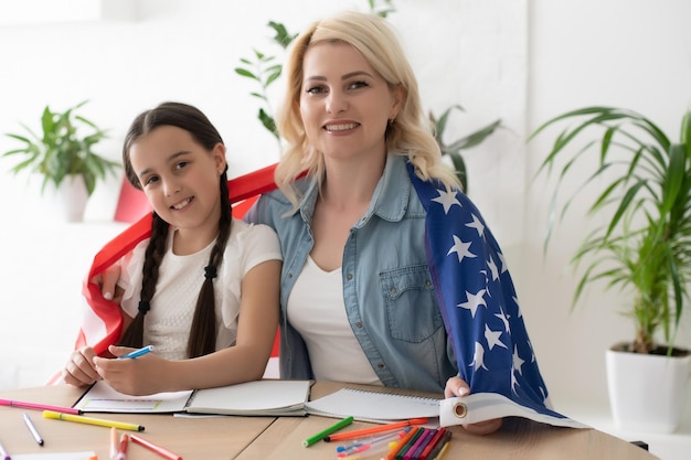 現在、宿題の手伝いは学童の間で広く求められています。アメリカで英語を学ぶ。背景にアメリカの国旗を持つ英語の女子学生。